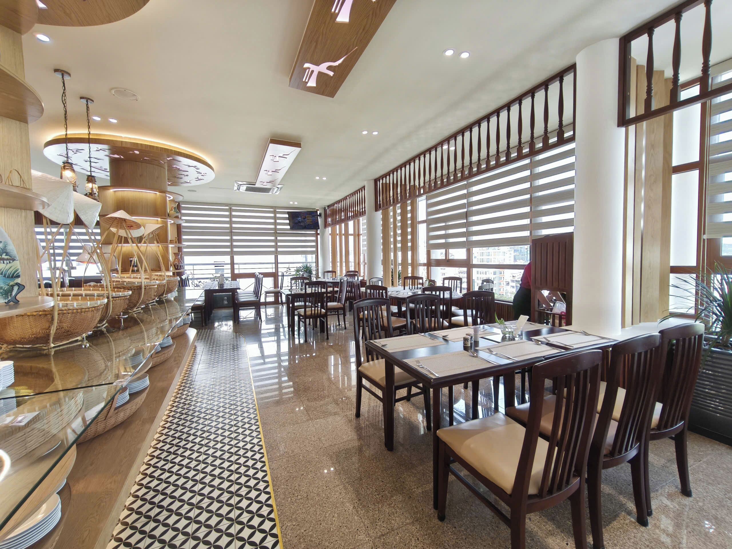 A spacious restaurant with high ceilings, large windows, and a polished floor.
