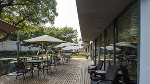 An outdoor patio with wooden flooring, tables, chairs, and umbrellas. - Metropolo Shanghai Minhang Hotel (Shanghai)