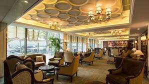 A spacious lobby with a high ceiling featuring circular patterns, multiple seating areas with sofas and armchairs, and a bar area visible through the windows. - Metropolo Shanghai Minhang Hotel (Shanghai)