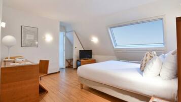 Une chambre à coucher avec un lit, un bureau, une chaise, une télévision et une fenêtre.