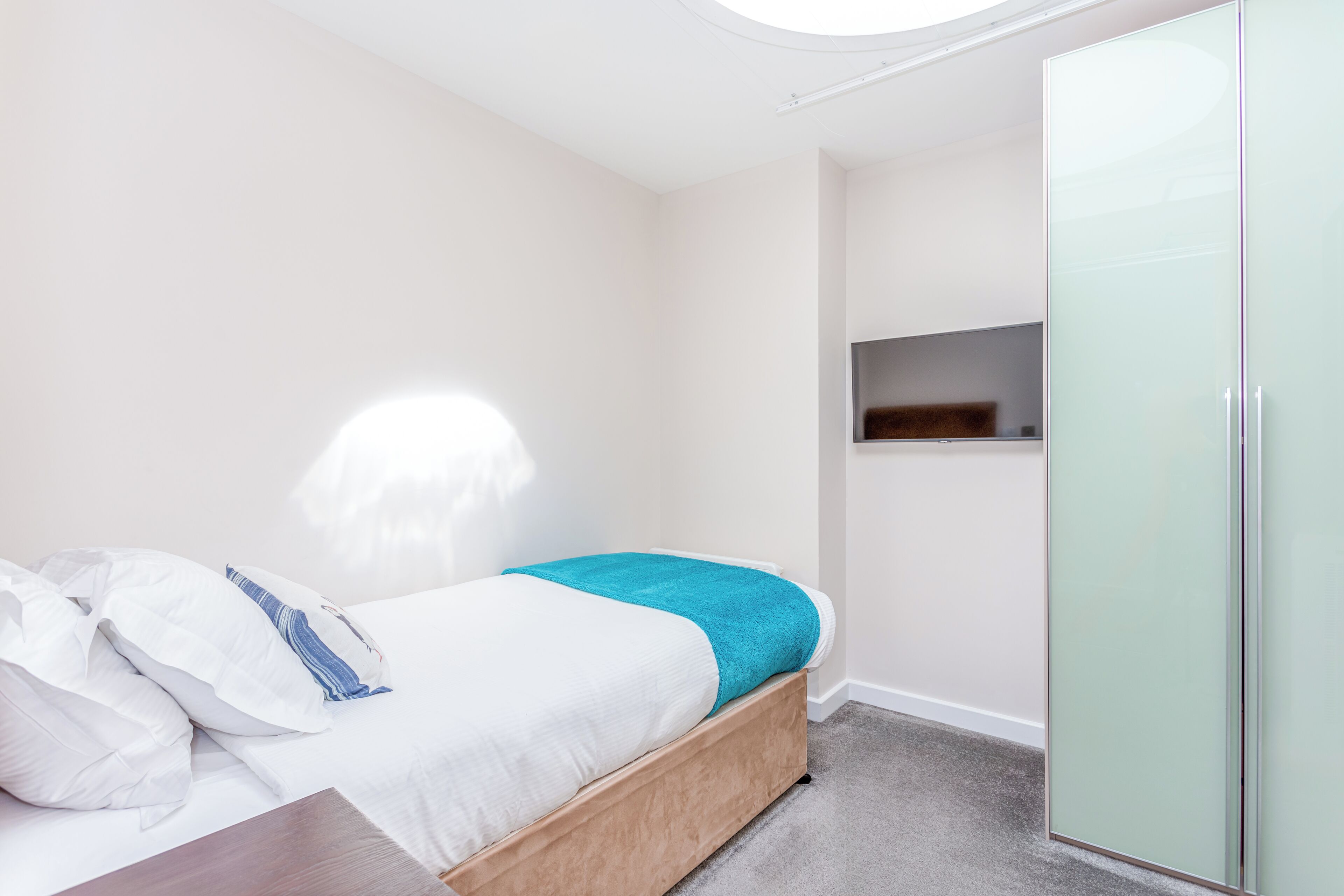 A bedroom with a bed, a wardrobe, and a small shelf.