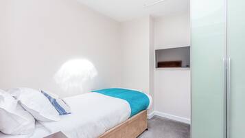 A bedroom with a bed, a wardrobe, and a small shelf.