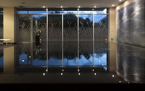 Eine moderne Lobby mit Glastrennwand, einer Bank und einem Topfpflanzen.