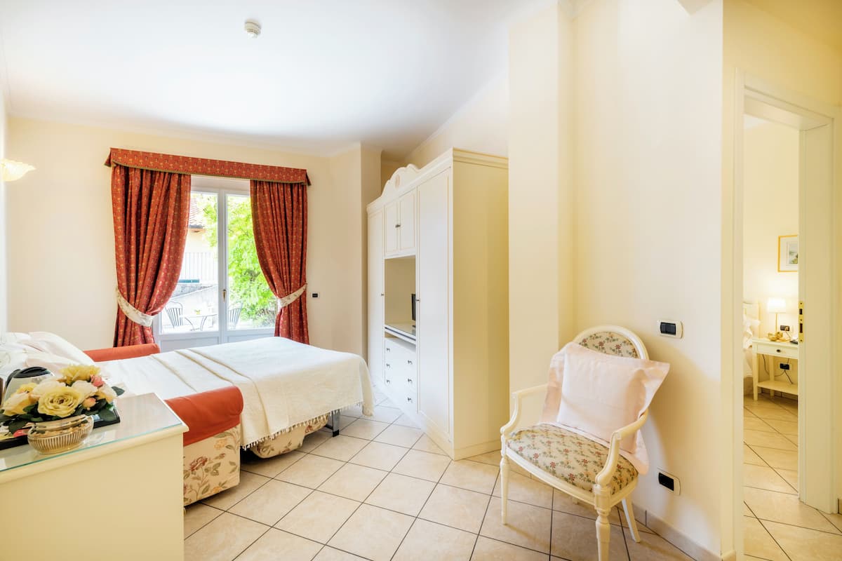 A bedroom with a bed, a chair, a wardrobe, and a window with curtains.