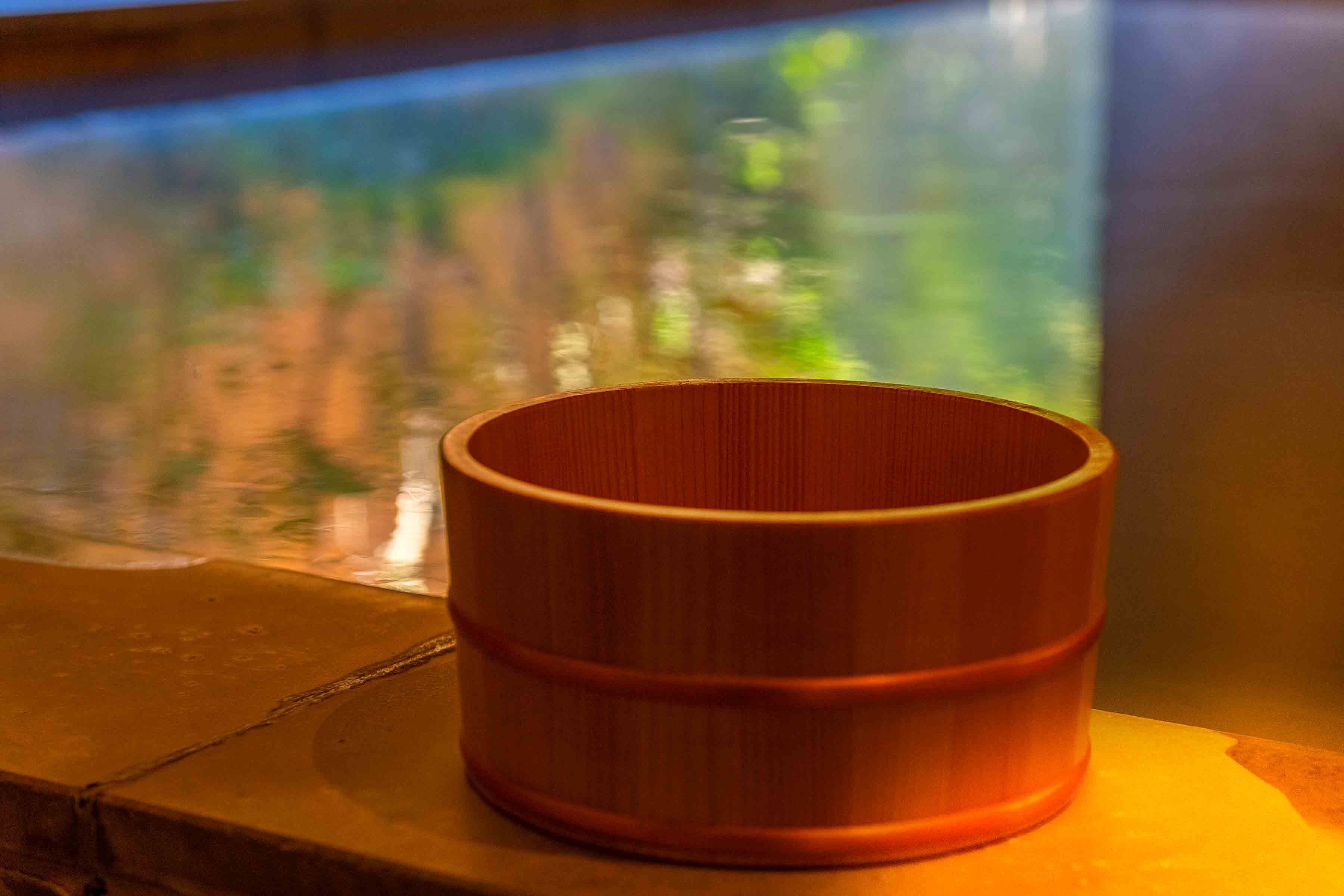 A wooden container on a ledge near a window with a view of a body of water.