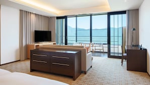 Habitación de hotel moderna con una cama grande, un televisor de pantalla plana, un escritorio y un balcón con vistas al mar.