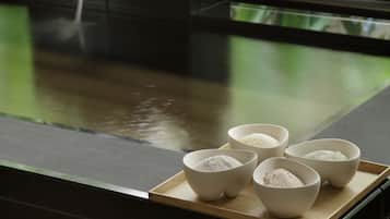 A kitchen counter with four bowls of rice, a water dispenser, and a potted plant.