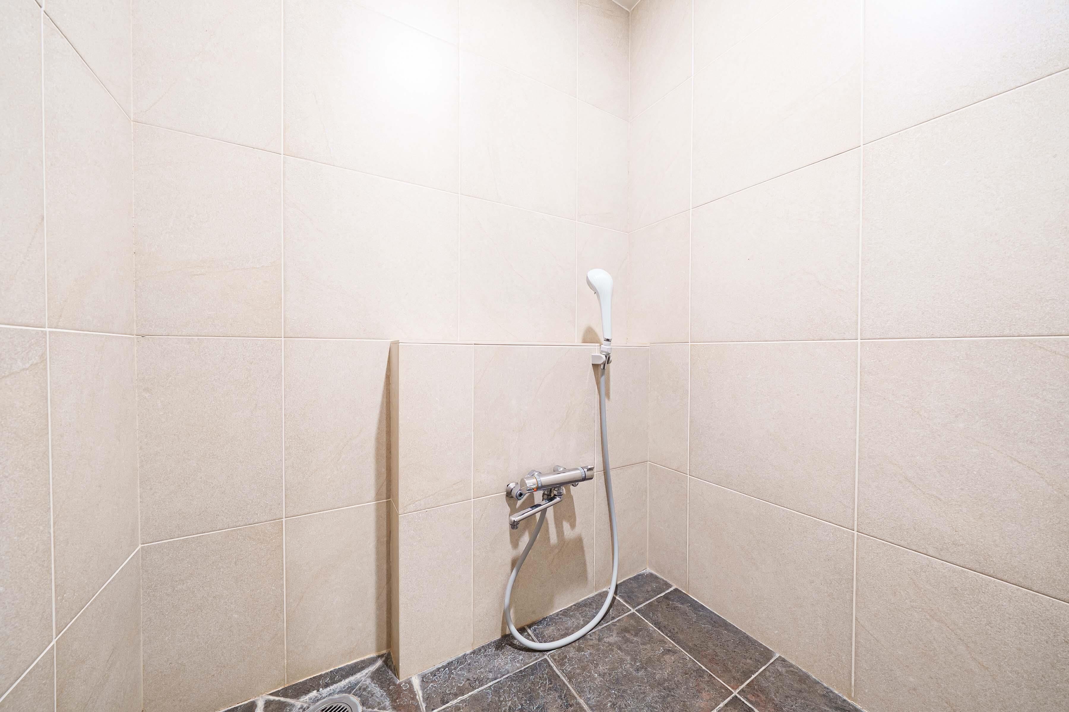 A shower area with beige tiles and a dark tiled floor.