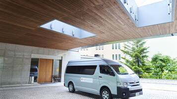 A modern building with a van parked in front, large windows, and a stone facade.