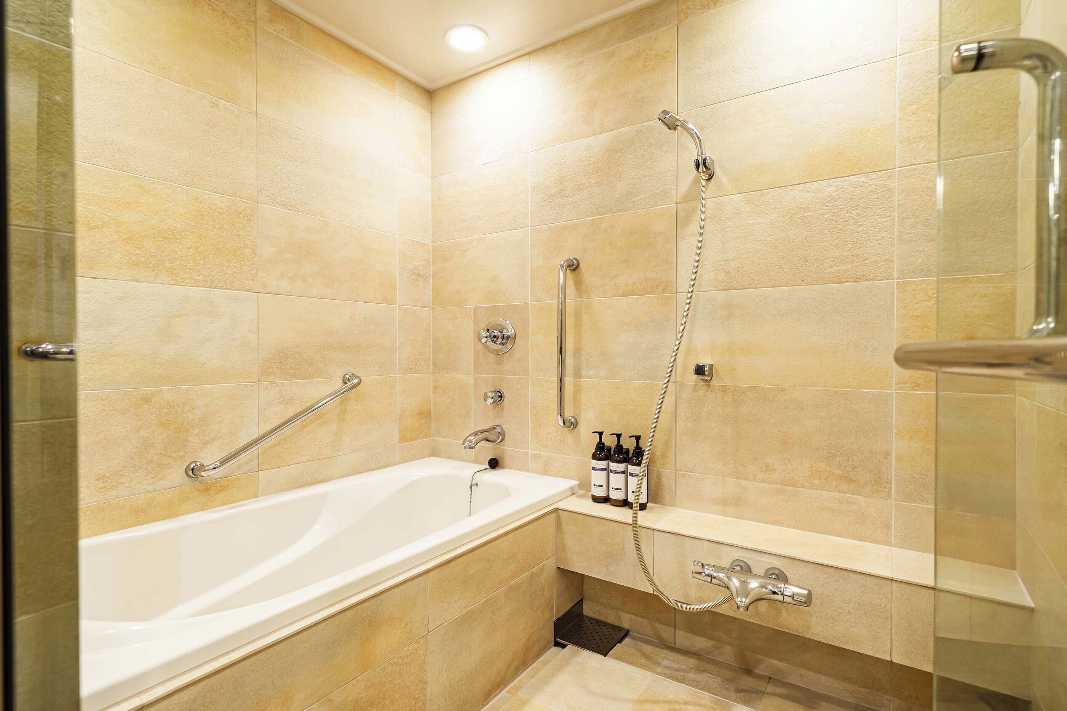 Un baño moderno con bañera, ducha y barras de apoyo.