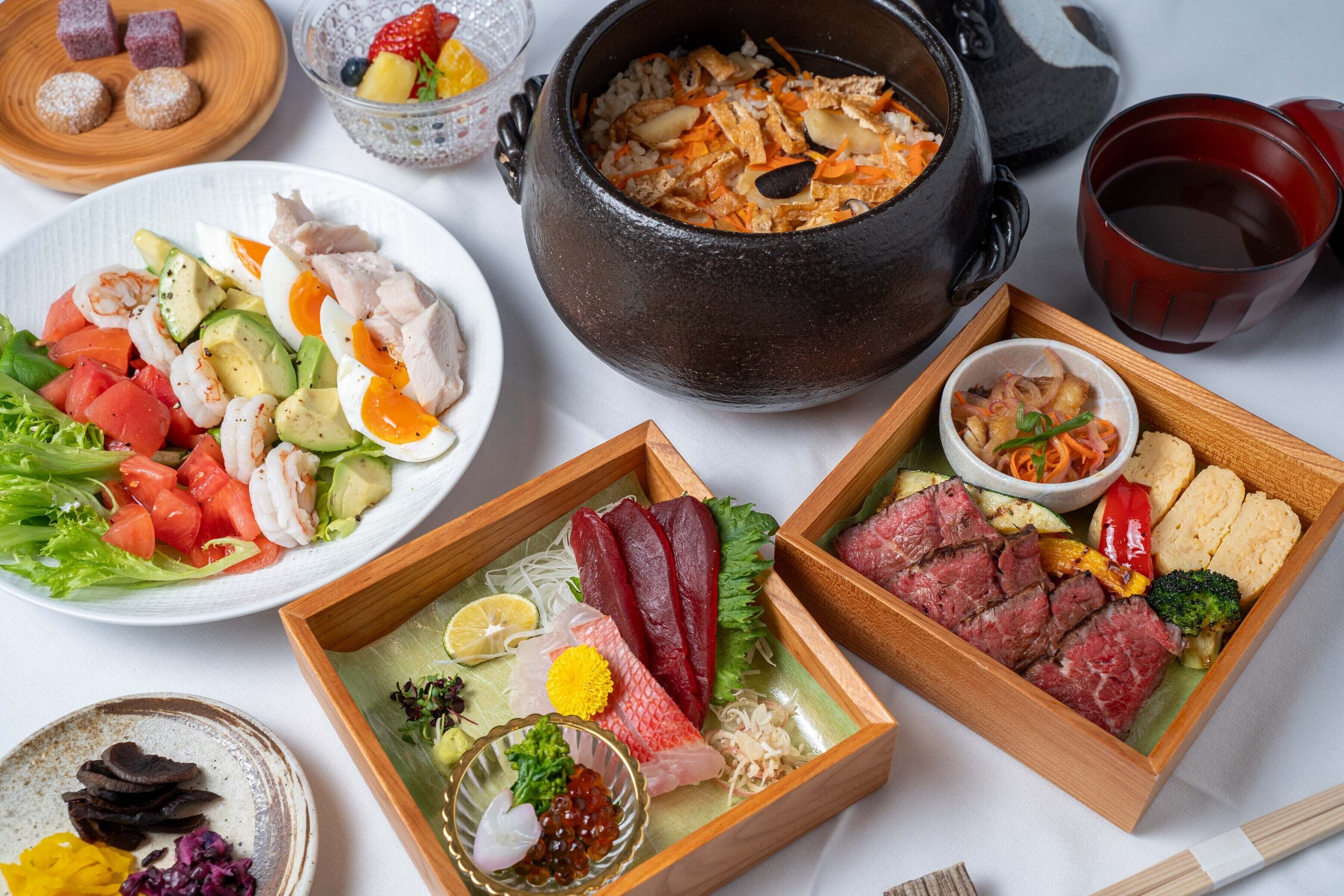 Diverse gerechten, waaronder sashimi, een pot rijst en een kom soep.