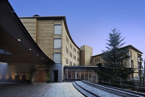 A modern building with a curved facade, large windows, and a paved entrance area. - Hyatt Regency Hakone Resort and Spa (Hakone)