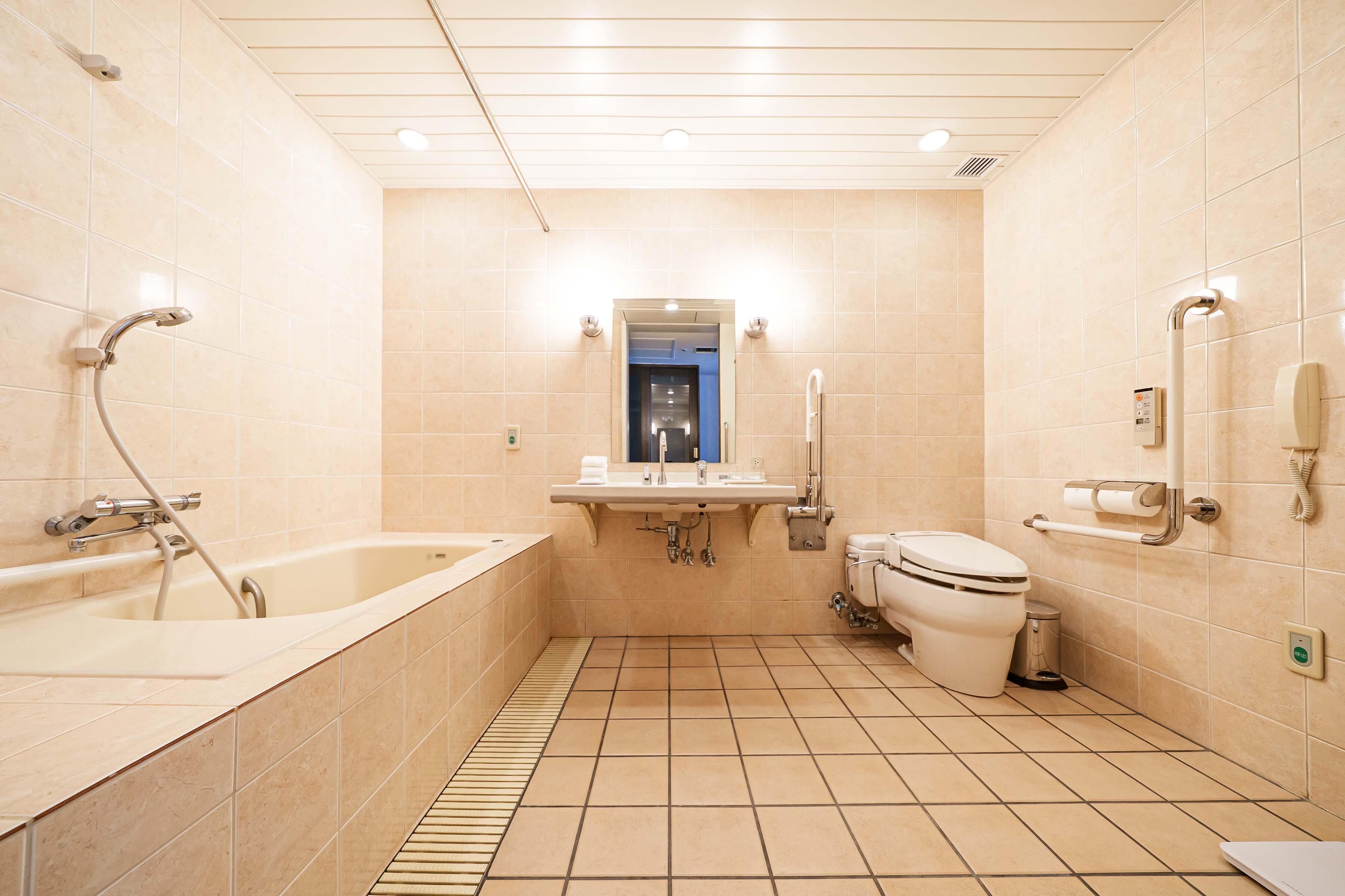 Un baño moderno con bañera, lavamanos, inodoro y un espejo sobre el lavamanos.