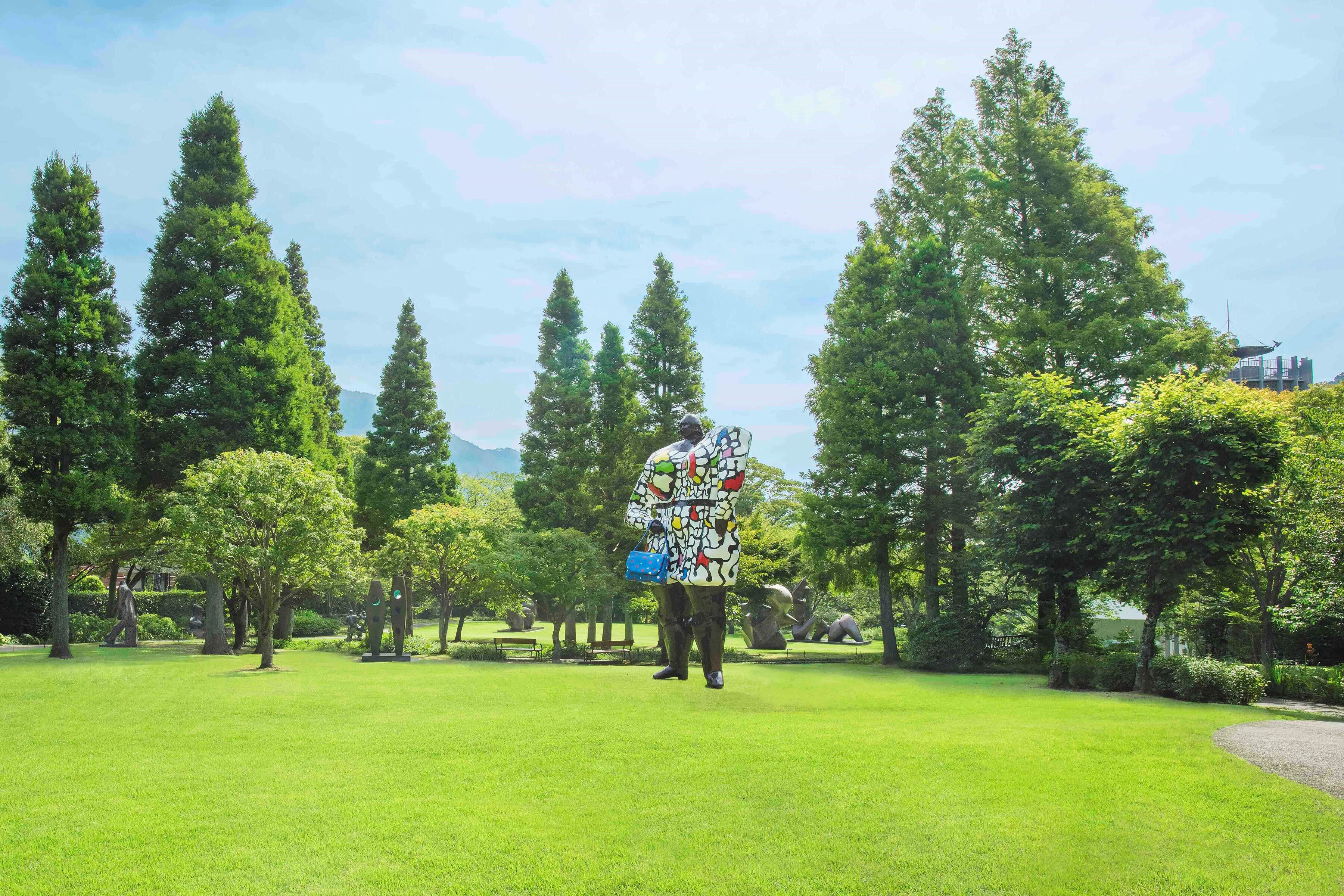A park with a statue of a person in a colorful outfit.