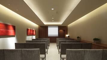 A conference room with rows of chairs, a projector screen, and a podium.