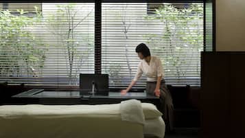 Una habitación con una mesa de masajes, una silla de masaje y un ventanal con persianas.
