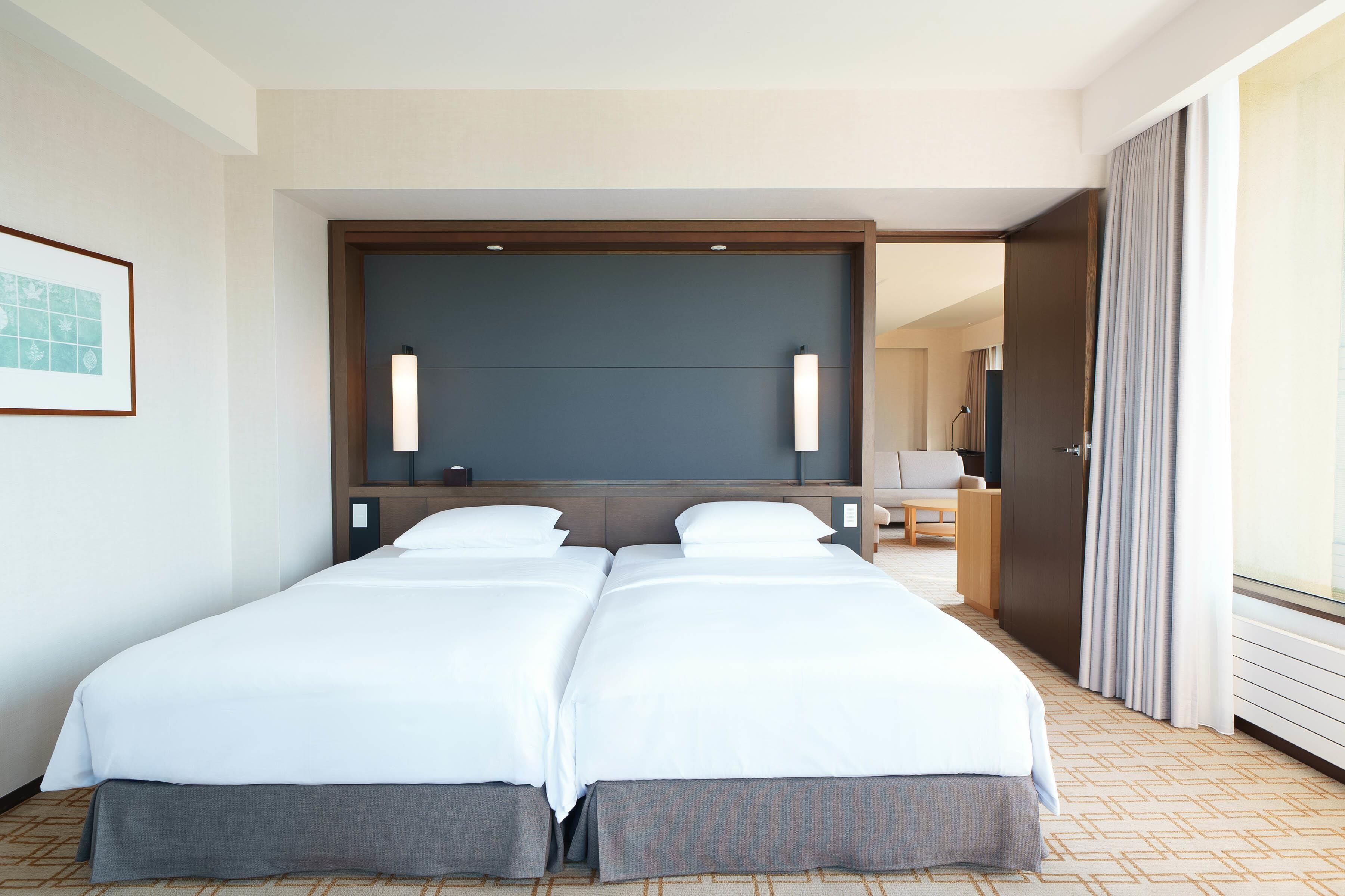 A hotel room with a large bed, a desk, a chair, and a mirror.