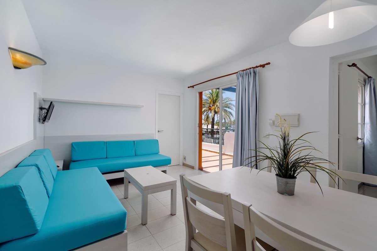 Un salon moderne avec un canapé bleu, une table blanche et une plante en pot.