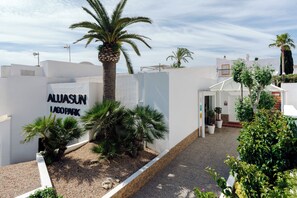 A gated entrance to a property named 'ALIASUN LAGOPARK' with a palm tree and potted plants. - Alua Lago Park (Ciutadella de Menorca)