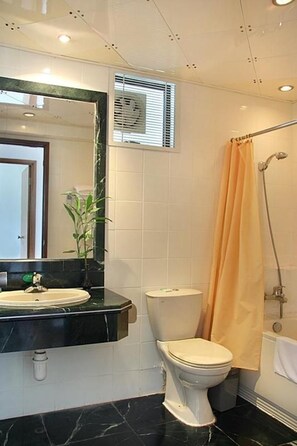 Un baño con inodoro, lavamanos y zona de ducha.