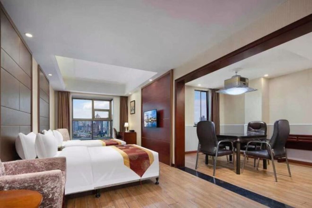 Habitación de hotel con una cama grande, un escritorio y sillas, y vistas a la ciudad.