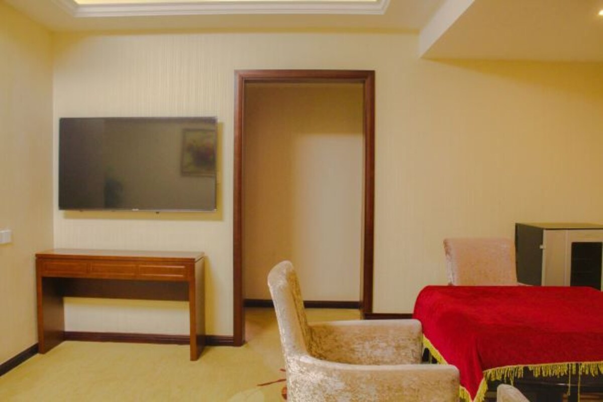Una habitación con cama, escritorio, silla, televisor y armario.