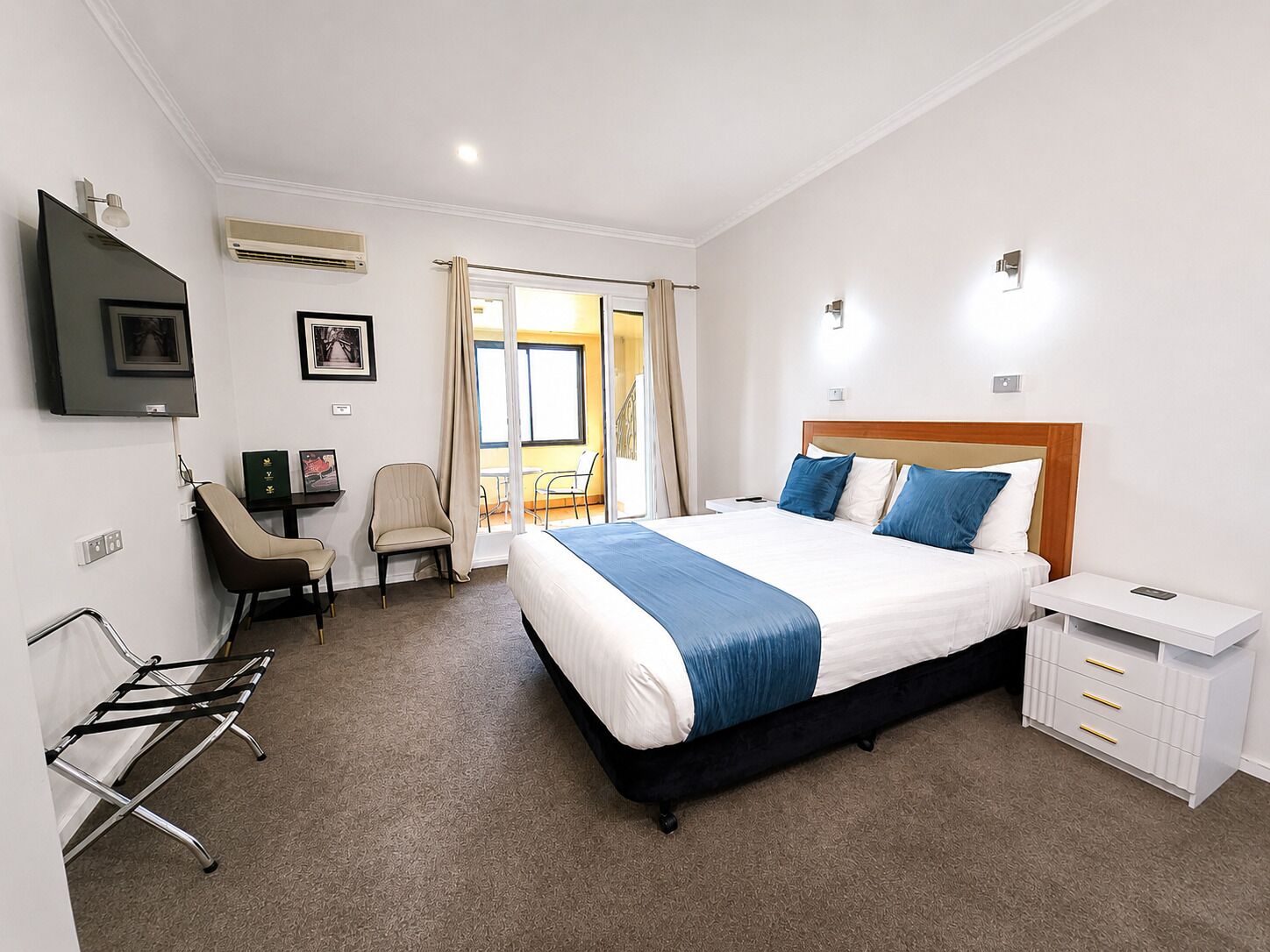 A hotel room with a bed, a desk, a chair, a TV, and a window.