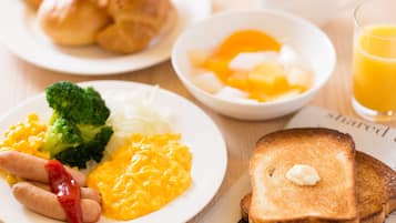Un piatto per la colazione con uova strapazzate, salsiccia, broccoli e formaggio.