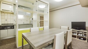 Una cocina moderna con armarios blancos, una mesa de comedor de madera y un televisor en una esquina.