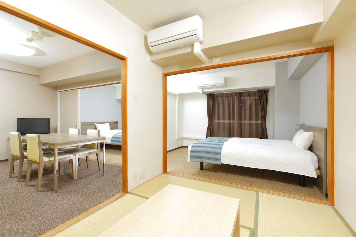Una habitación de hotel con cama, escritorio, silla, televisor y aire acondicionado.