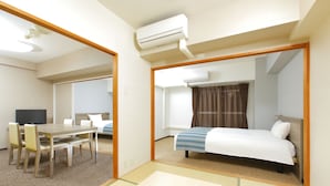 Una habitación de hotel con cama, escritorio, silla, televisor y aire acondicionado.