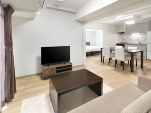 Una sala de estar moderna con televisor de pantalla plana, una mesa de centro y un sofá.
