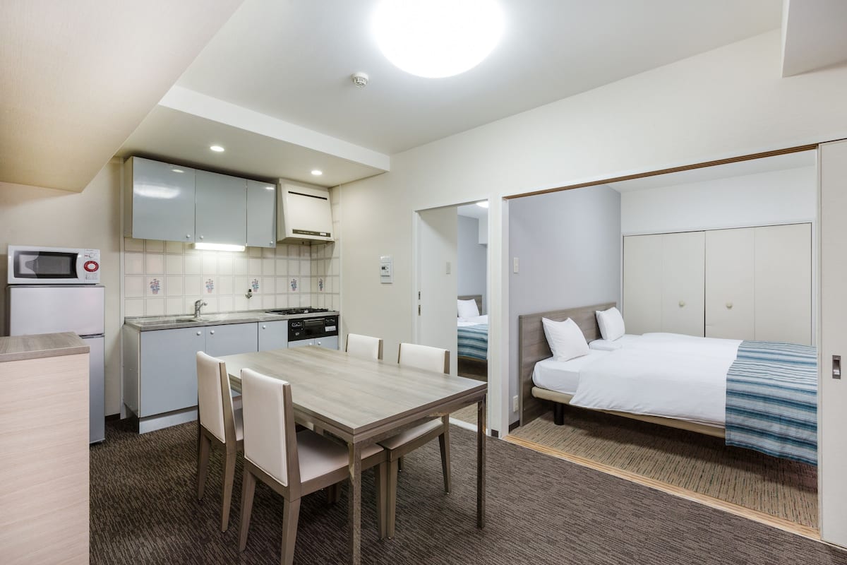 Una habitación de hotel compacta con kitchenette, comedor y cama.