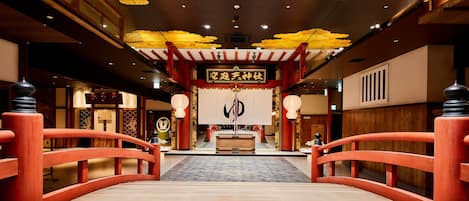 A traditional Japanese interior with a wooden bridge leading to a central altar.