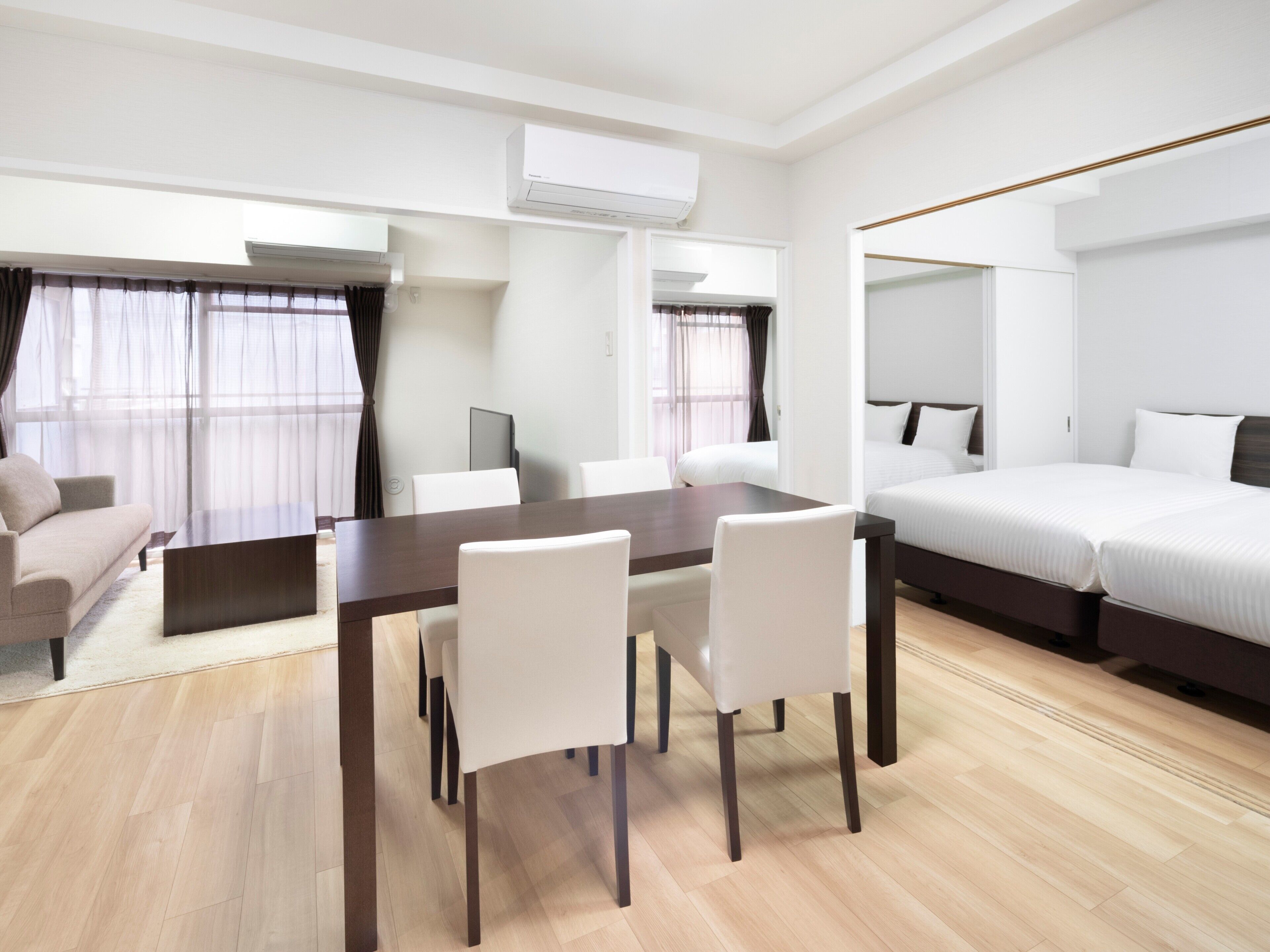 Una habitación de hotel moderna con zona de comedor, cama y aire acondicionado.