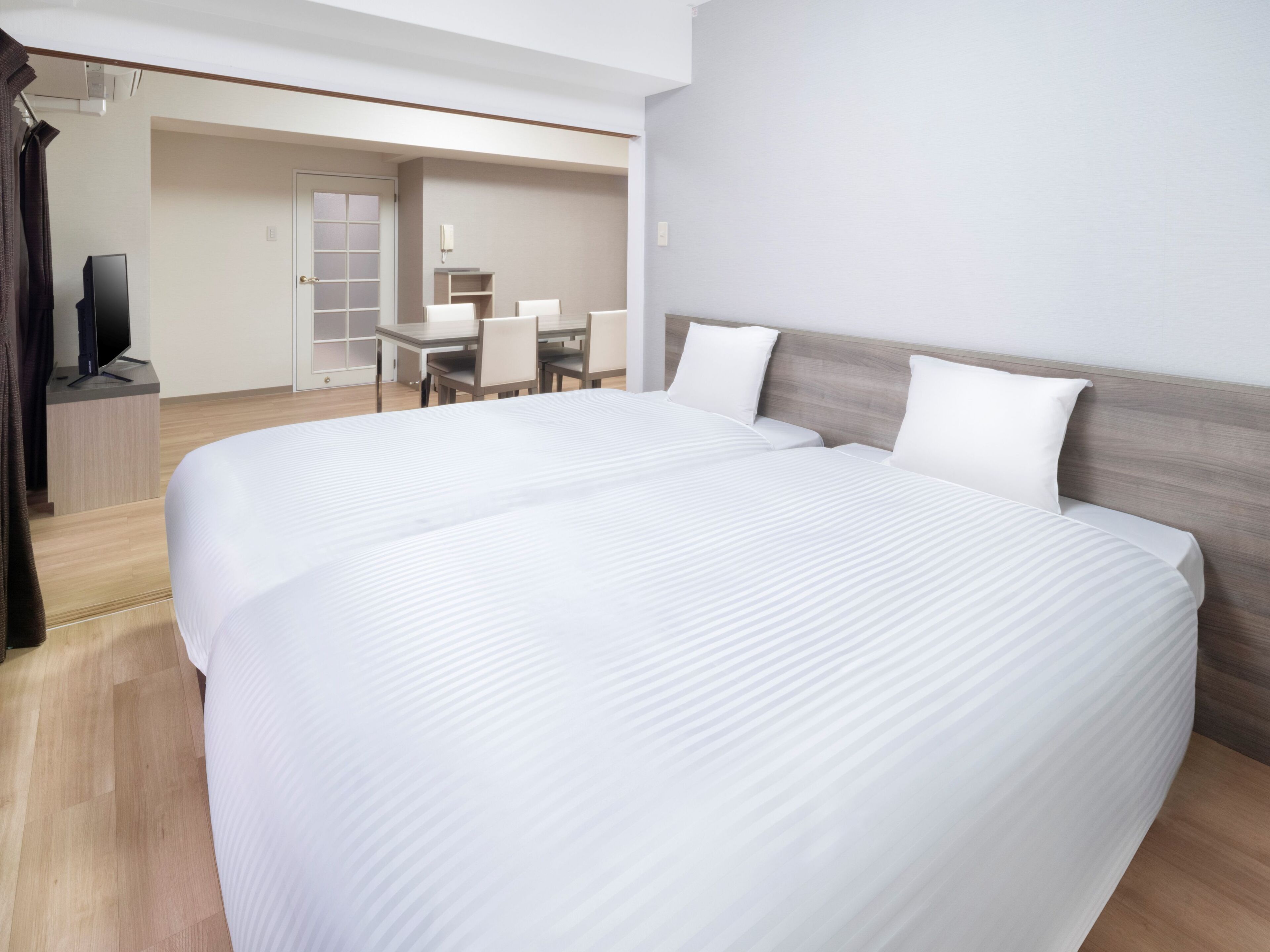 Quarto de hotel com duas camas, uma escrivaninha e uma televisão.