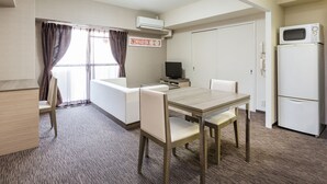 Una habitación de hotel compacta con una mesa de comedor, sillas, televisor, microondas y armario.