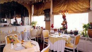 Un comedor con mesas dispuestas para una comida, sillas y una araña.