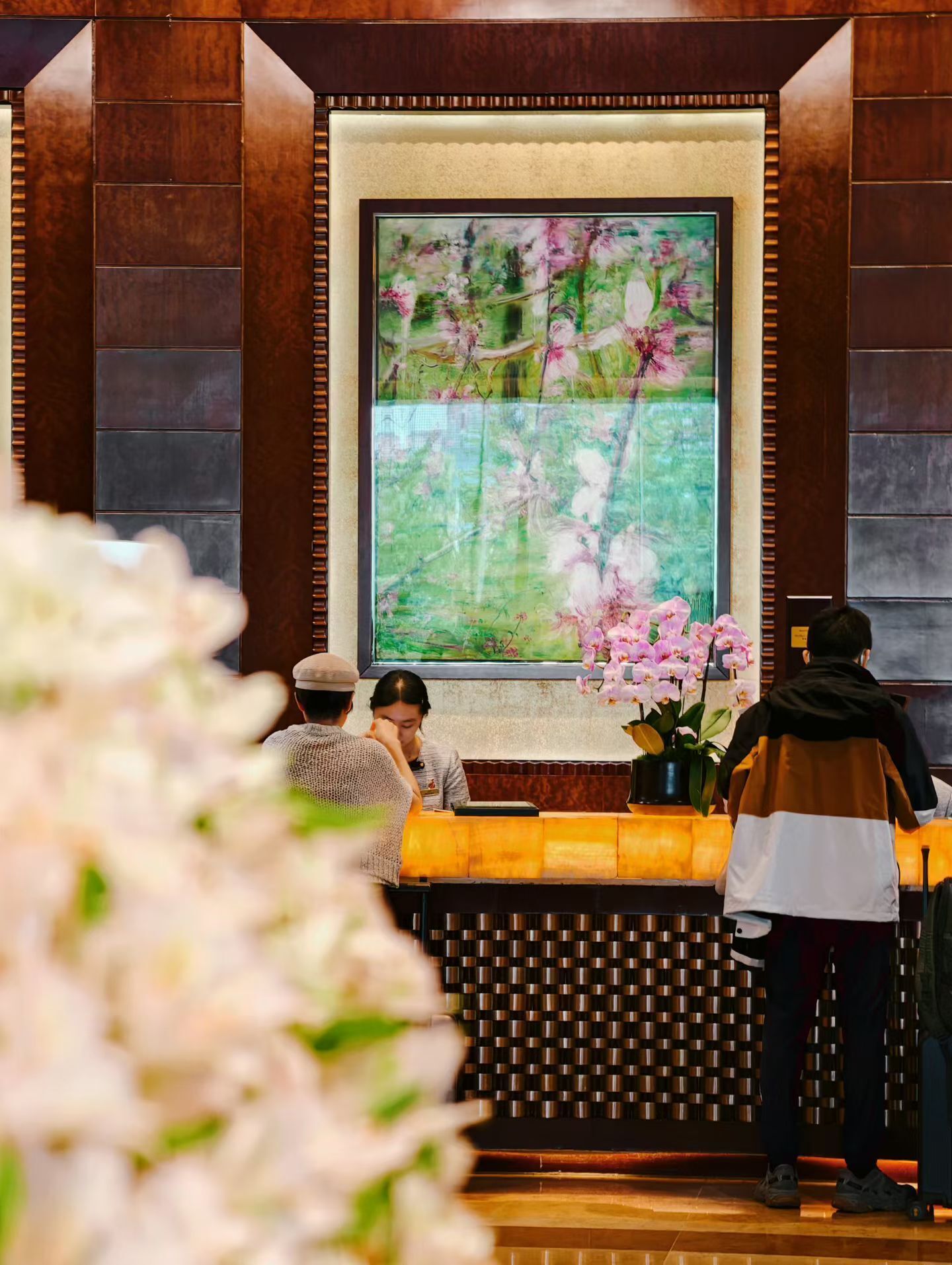 A reception area with a large digital screen displaying a floral image, a reception desk, and a seating area.