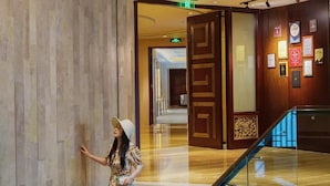 A woman standing on a staircase in a hotel lobby with a decorative ceiling and wall-mounted plaques. - Shangri-La Chengdu (Chengdu)