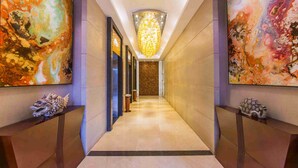Un couloir au design moderne, agrémenté d’un luminaire central, d’œuvres d’art murales abstraites et de sculptures décoratives disposées de part et d’autre.