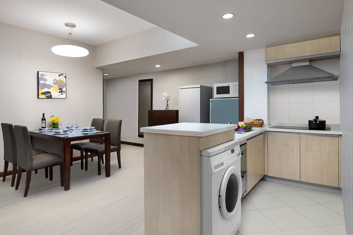 A modern kitchen with a built-in washer and dryer, a dining area with a table and chairs, and a microwave above the counter.