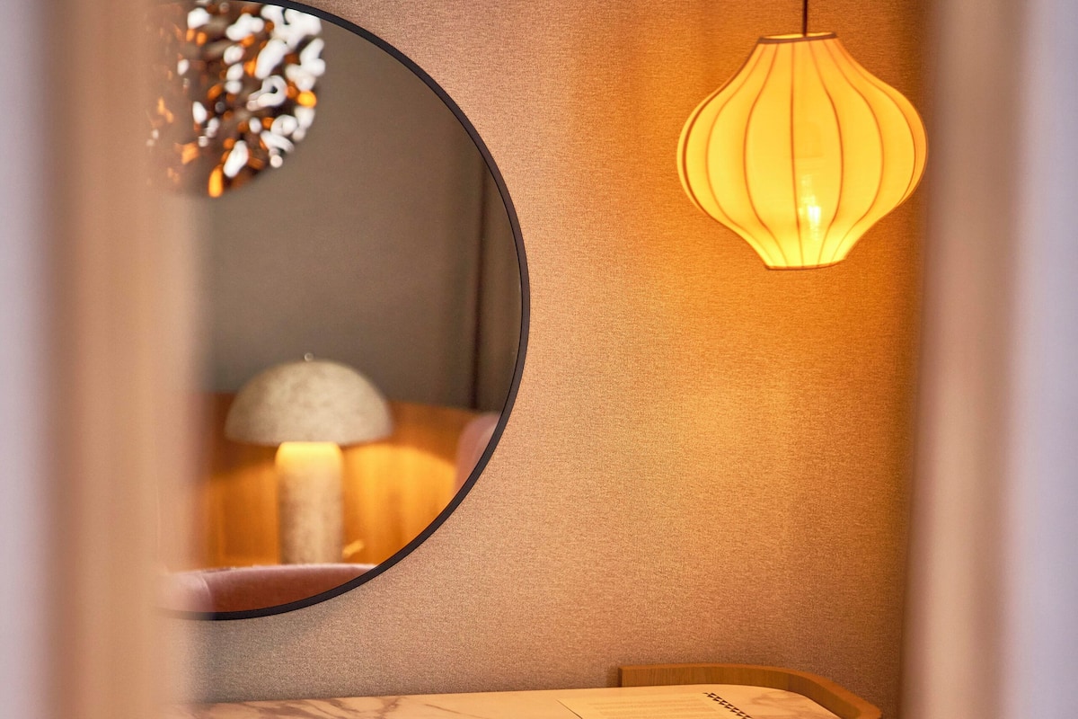 Ein Zimmer mit einem runden Spiegel, einem Tisch und einem Stuhl.