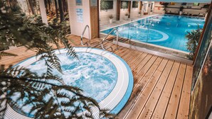 Una piscina interior con cubierta de madera y un jacuzzi.