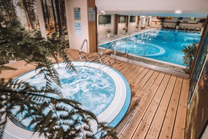 Relax by the central hot tub surrounded by a deck, overlooking a forest-themed mural.