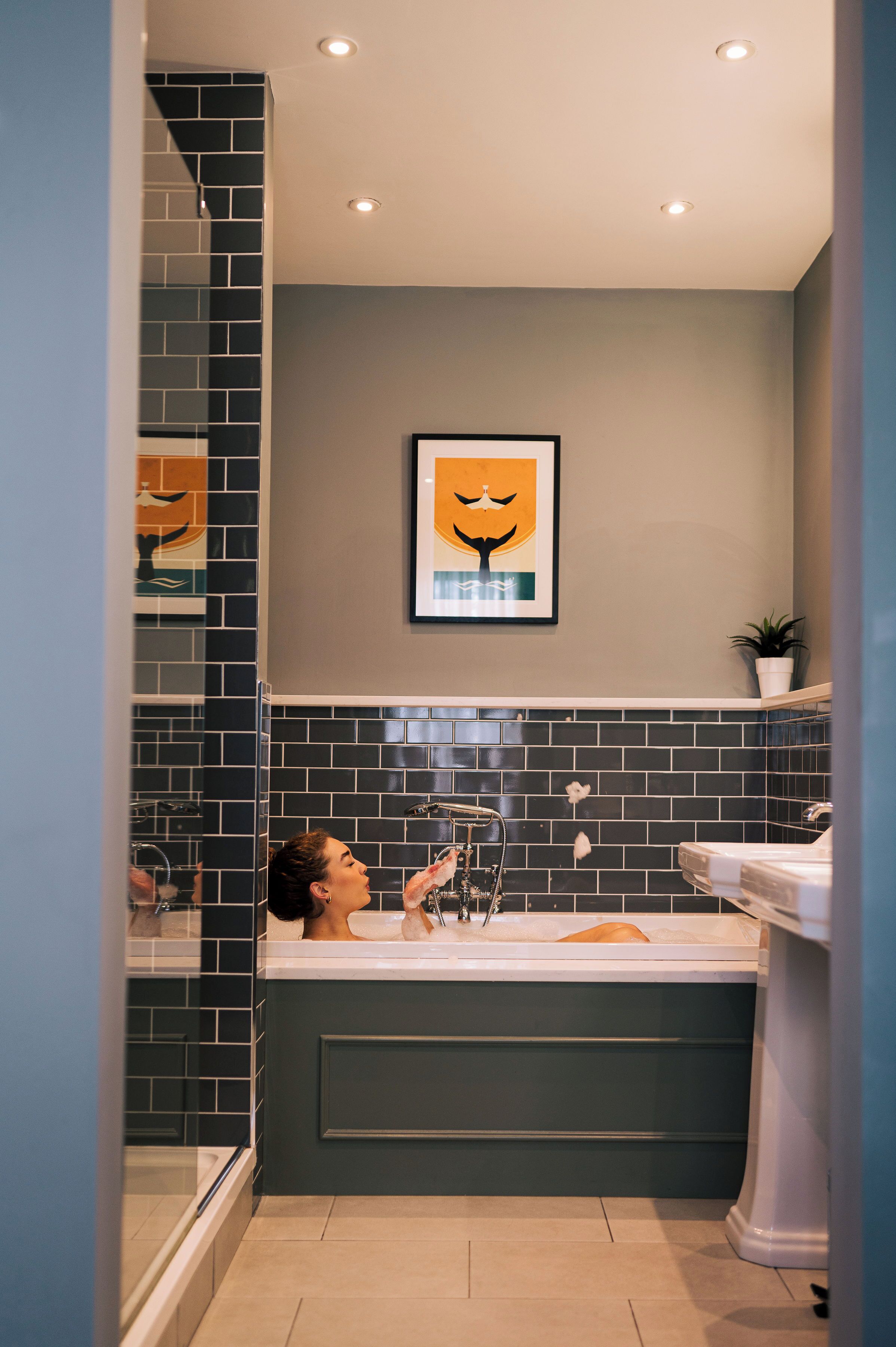 A bathroom with a bathtub, a shower, and a sink. There is a framed artwork on the wall above the bathtub.