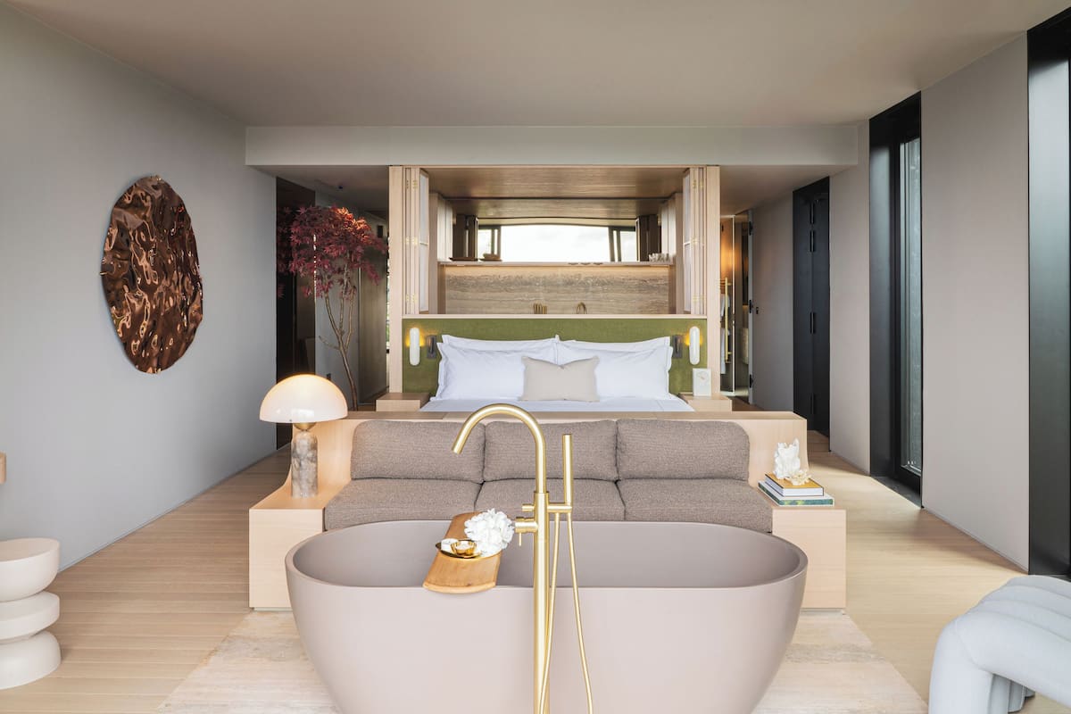 Ein modernes Schlafzimmer mit einer großen Badewanne, einem Sofa und einem Nachttisch mit Lampe.