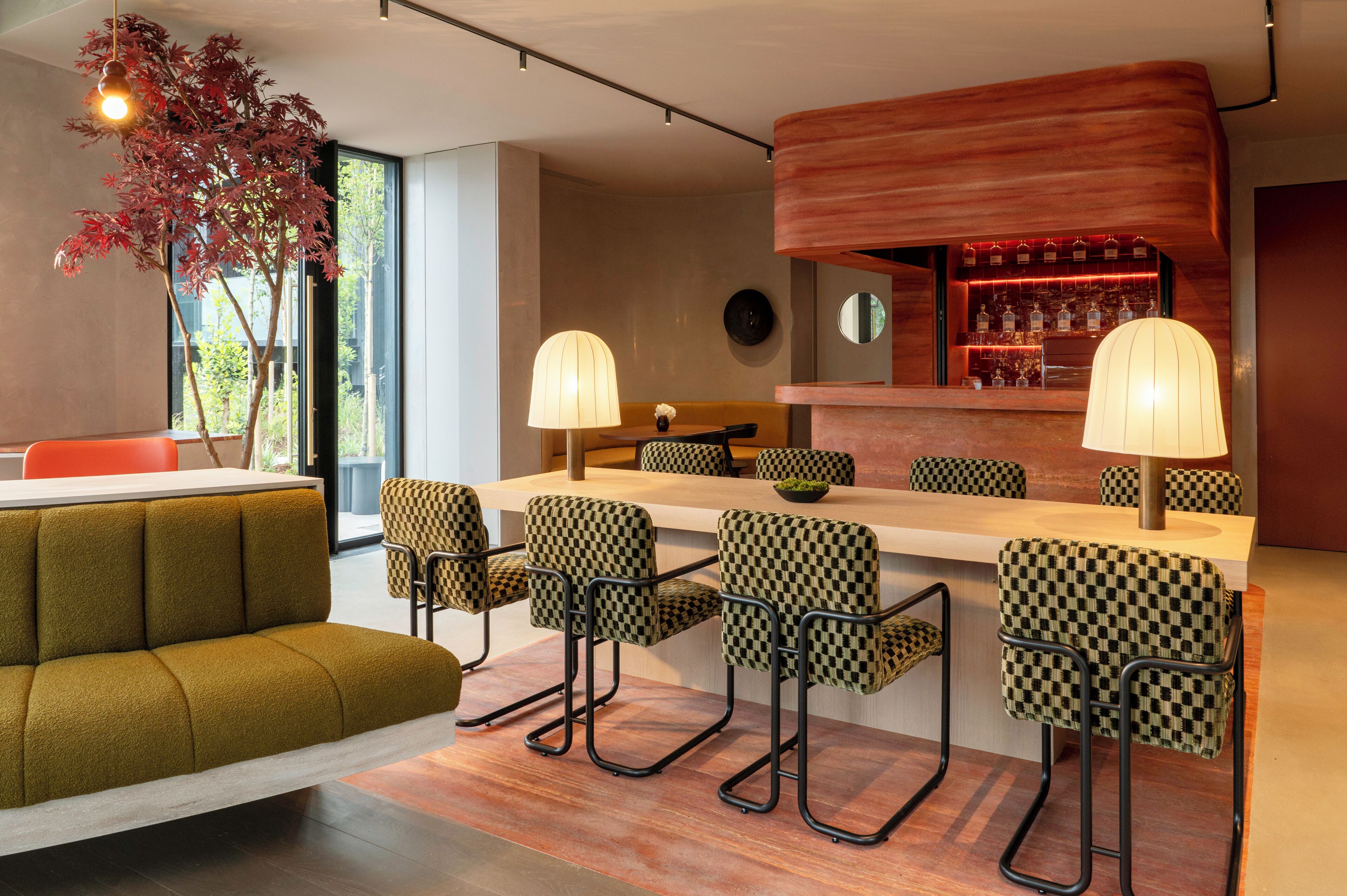 A modern bar area with checkered bar stools, a wooden bar counter, and a seating area with a sofa and chairs.