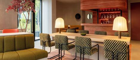 A modern bar area with checkered bar stools, a wooden bar counter, and a seating area with a sofa and chairs.