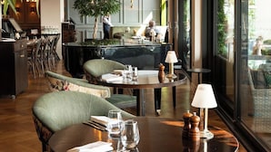 Un comedor moderno con mesas redondas, asientos cómodos y un amplio ventanal con vistas al exterior.